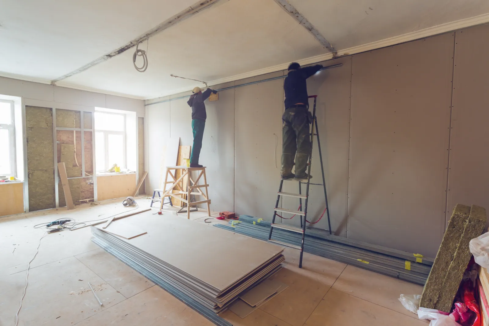 A remodeling crew hanging drywall in a gutted room